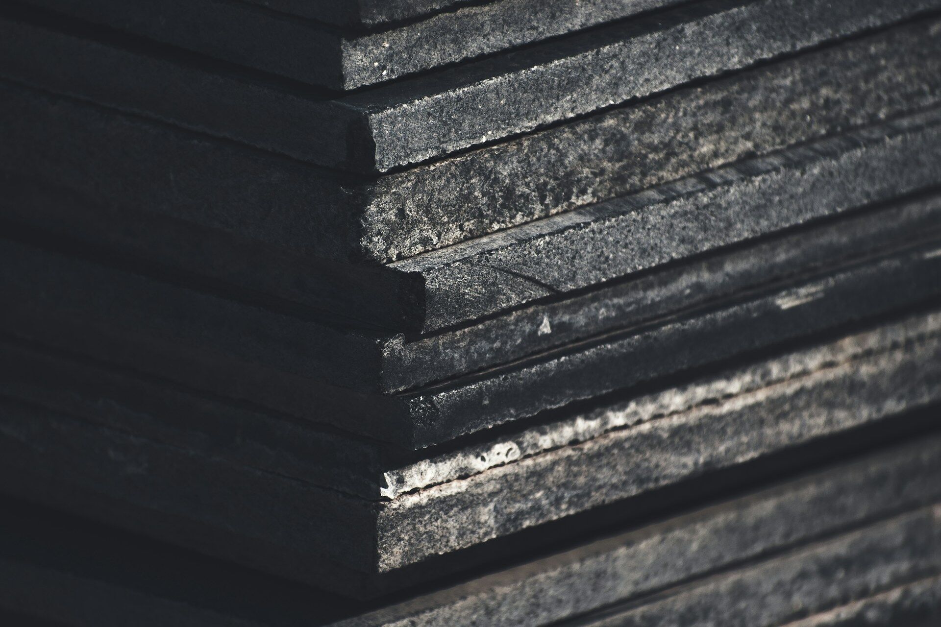 Close-up of stacked dark stone slabs showing rough texture and edges