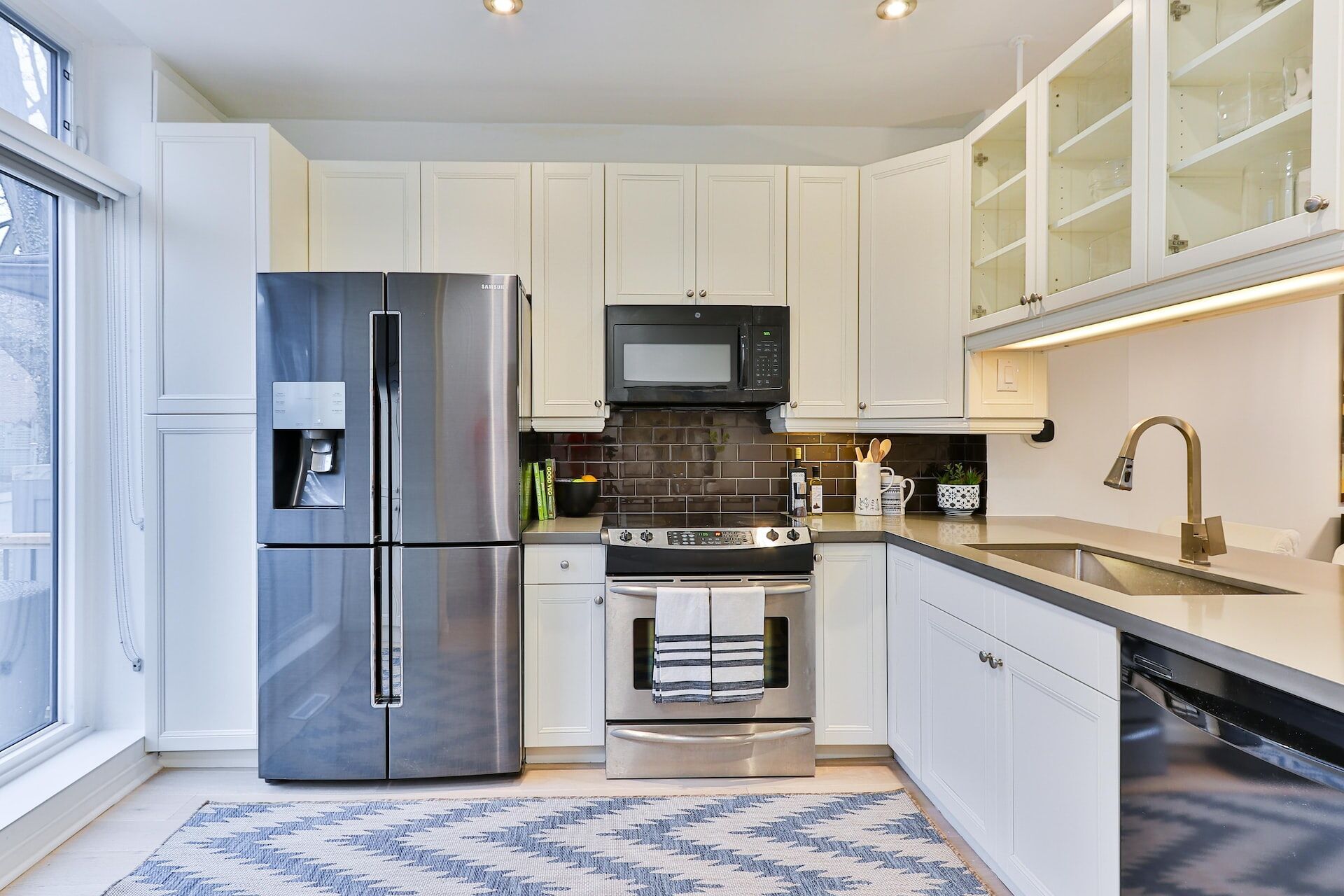 Modern kitchen featuring white cabinets, stainless steel appliances, and a dark subway tile backsplash
