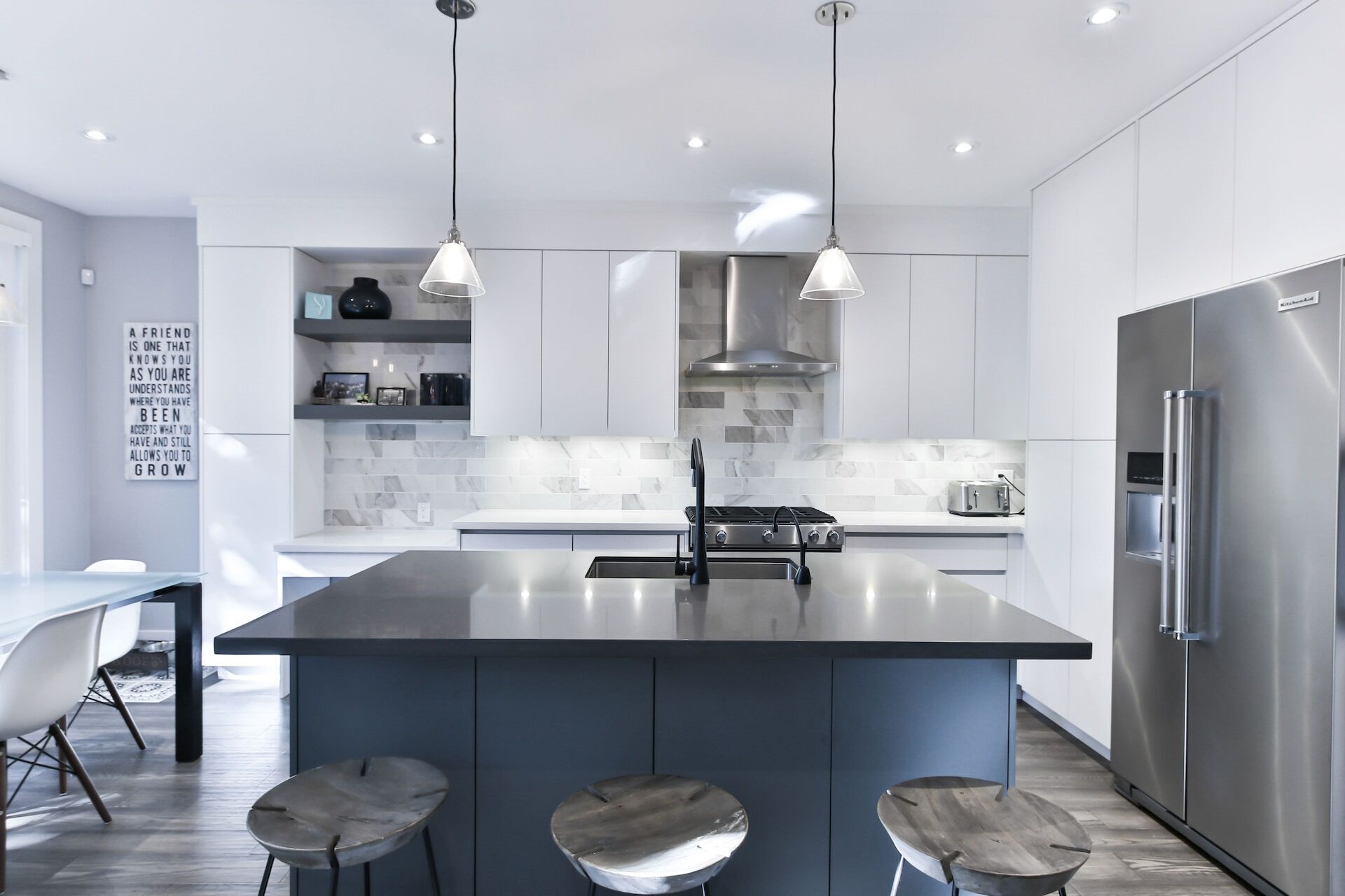 Modern kitchen featuring a dark granite island, stainless steel appliances, and white cabinets
