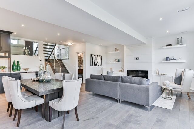Spacious living room with gray sofa, dining area, and light wood floors, showcasing modern decor