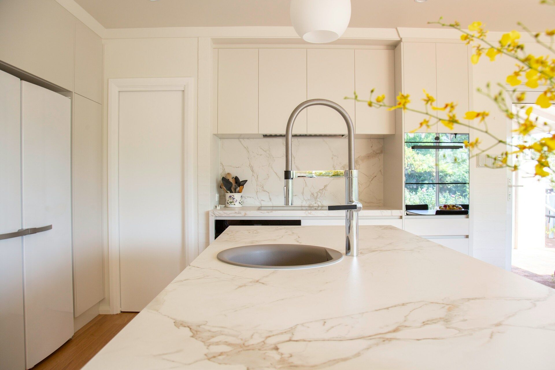Modern kitchen with marble countertop, built-in sink, and sleek faucet, with yellow flowers in the foreground