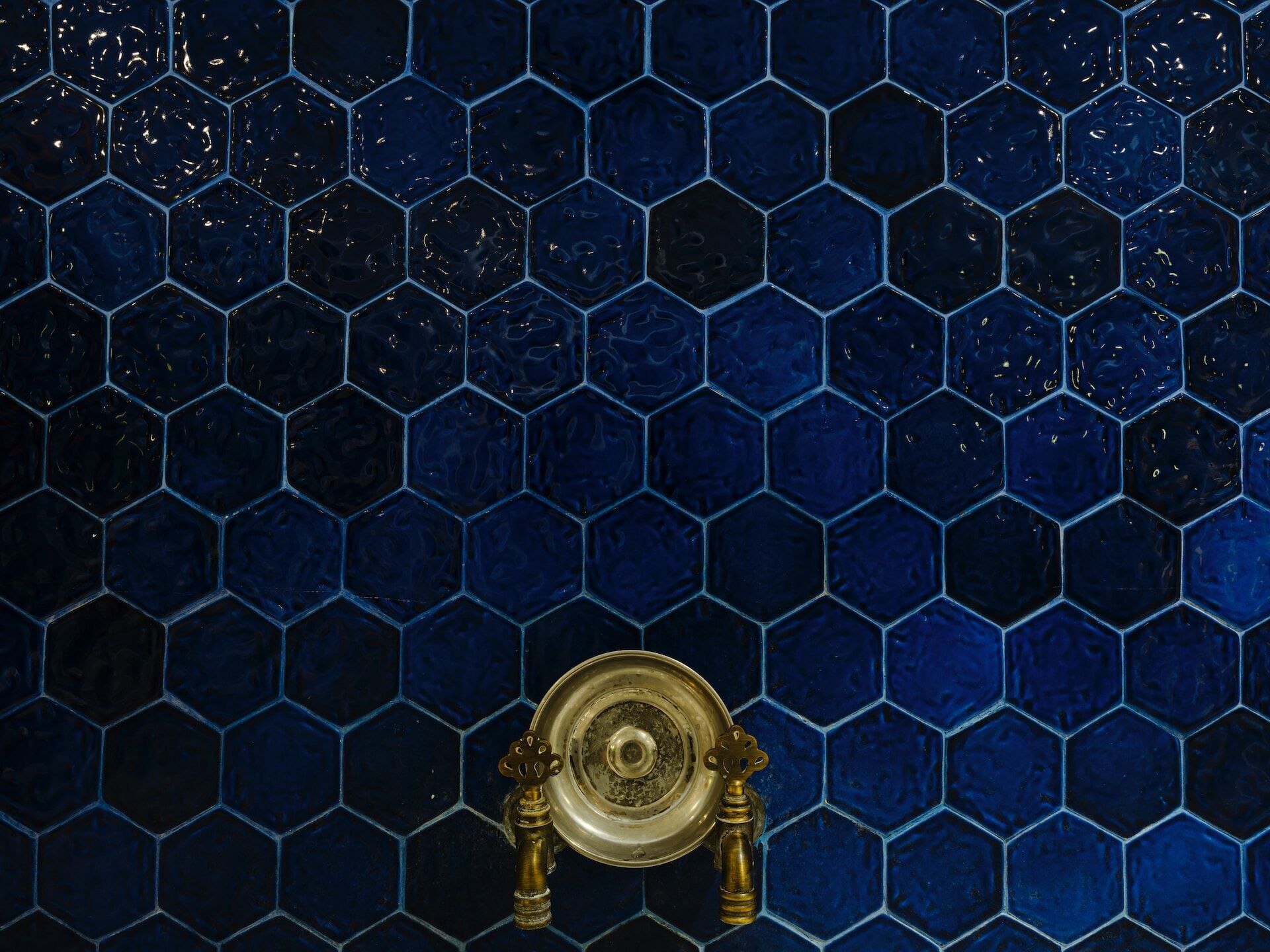 Dark blue hexagonal tiles with a vintage brass faucet in the center