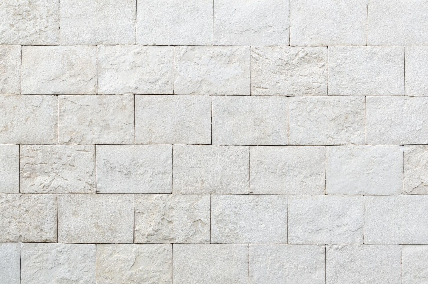Close-up of a wall with rectangular white stone tiles in a staggered pattern