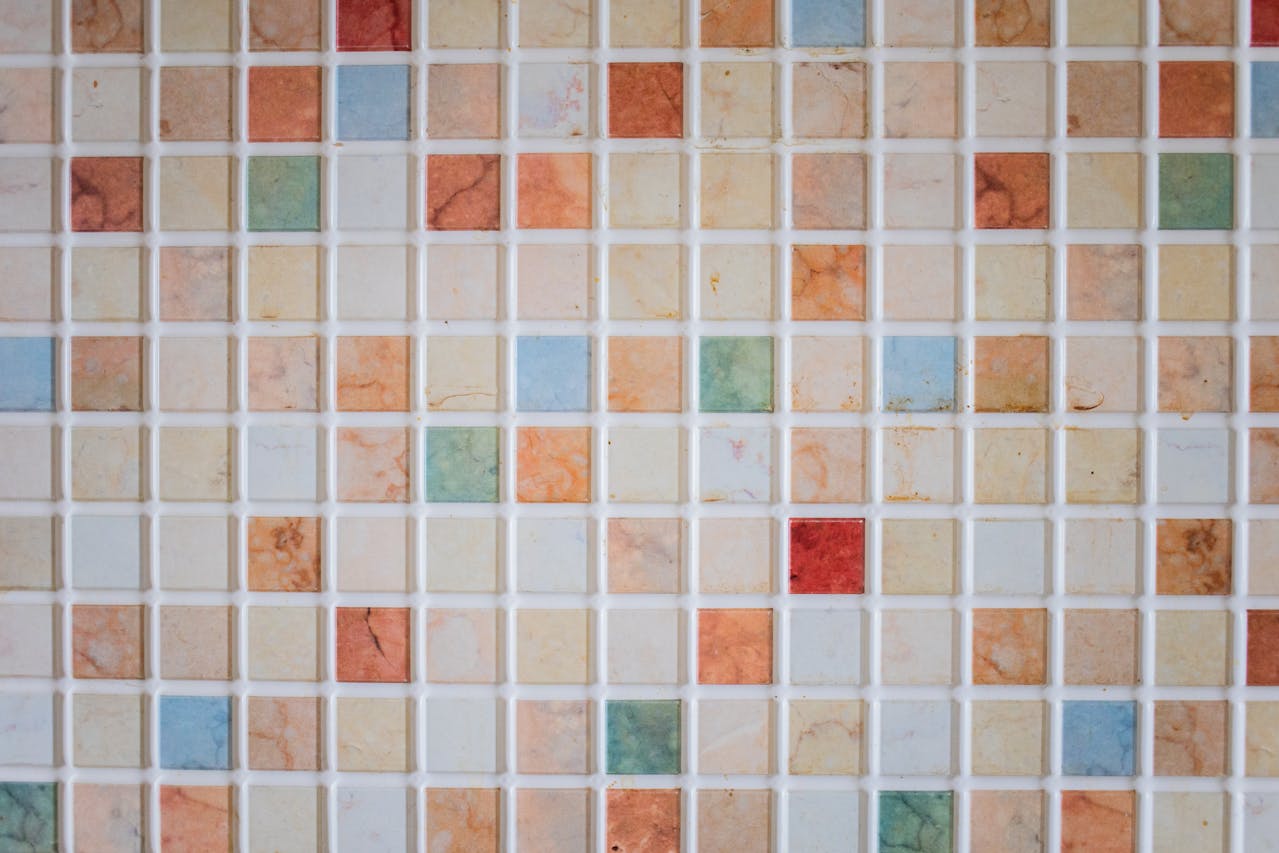 Close-up of a colorful mosaic tile pattern with small square tiles in orange, blue, green, and beige