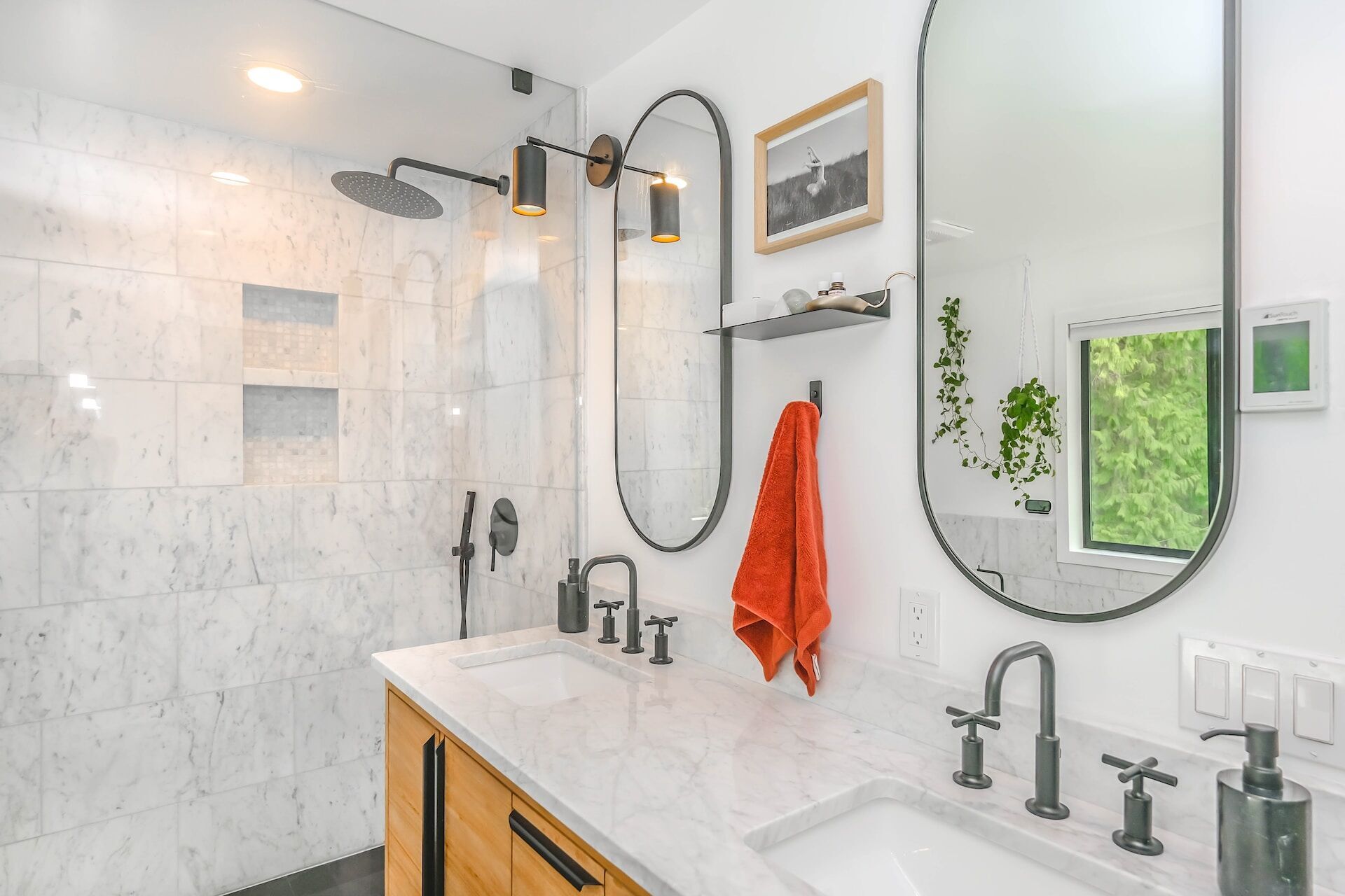 Modern bathroom with marble tiles, double vanity, and oval mirrors